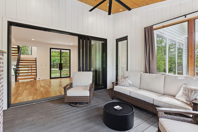 living room featuring wood finished floors, a ceiling fan, wooden ceiling, stairway, and wooden walls