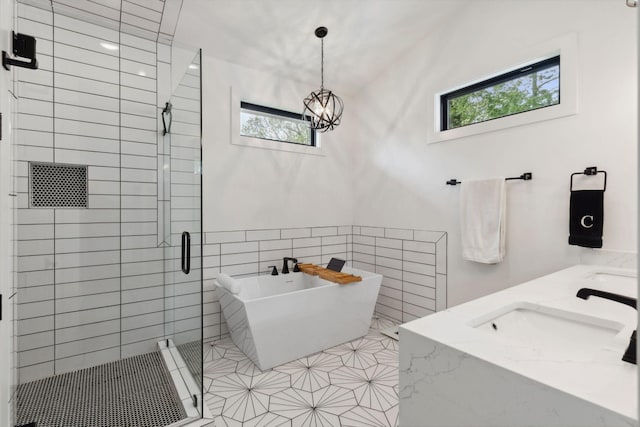 bathroom with a sink, tile walls, a freestanding bath, a shower stall, and a chandelier
