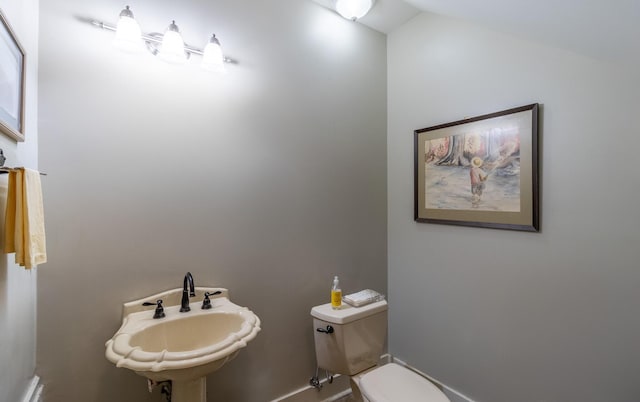 bathroom featuring a sink, toilet, and lofted ceiling