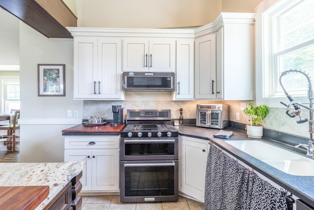 kitchen featuring stainless steel appliances, a sink, tasteful backsplash, and plenty of natural light