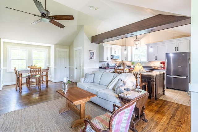 living room with lofted ceiling, a ceiling fan, and light wood-style flooring