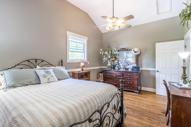bedroom featuring light wood-style flooring, vaulted ceiling, baseboards, and a ceiling fan