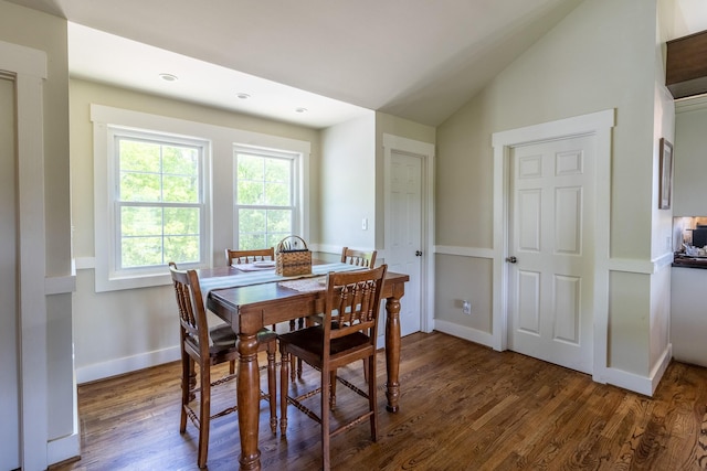 dining area featuring dark wood-type flooring, baseboards, and vaulted ceiling