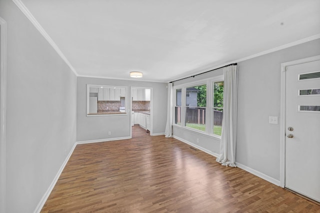 unfurnished living room with ornamental molding, wood finished floors, and baseboards