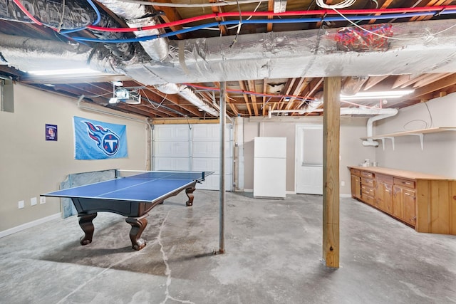 below grade area featuring freestanding refrigerator and baseboards