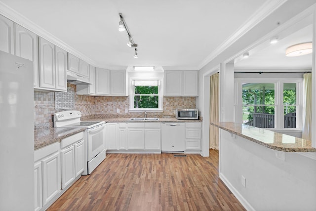 kitchen featuring white appliances, a sink, light wood-style flooring, tasteful backsplash, and white cabinetry