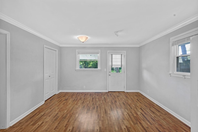 unfurnished room featuring healthy amount of natural light, hardwood / wood-style floors, baseboards, and crown molding