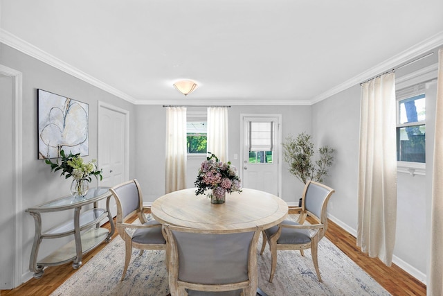 dining room featuring baseboards, wood finished floors, and ornamental molding