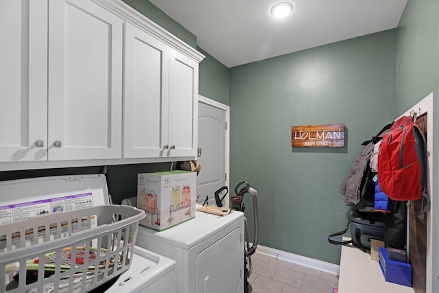 laundry area featuring washing machine and dryer, cabinet space, light tile patterned floors, and baseboards