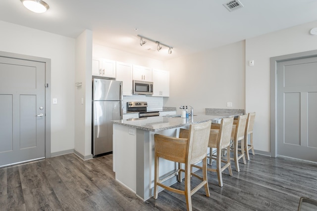 782 Riverfront Pkwy Unit 216, Chattanooga, TN 37402 - kitchen featuring appliances with stainless steel finishes, a peninsula, dark wood-style floors, a breakfast bar area, and decorative backsplash