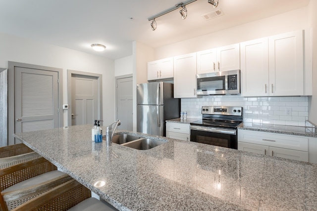 782 Riverfront Pkwy Unit 216, Chattanooga, TN 37402 - kitchen featuring appliances with stainless steel finishes, a sink, a breakfast bar area, white cabinets, and light stone countertops