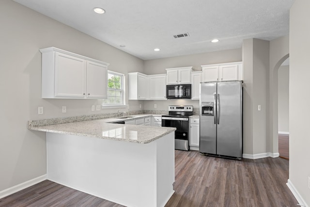 5029 Luker Ln, Antioch, TN 37013 - kitchen with stainless steel appliances, arched walkways, white cabinets, a peninsula, and dark wood-type flooring