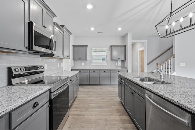 1132 General Marshall Ct, Murfreesboro, TN 37129 - kitchen featuring appliances with stainless steel finishes, a sink, gray cabinets, light stone counters, and light wood-style flooring