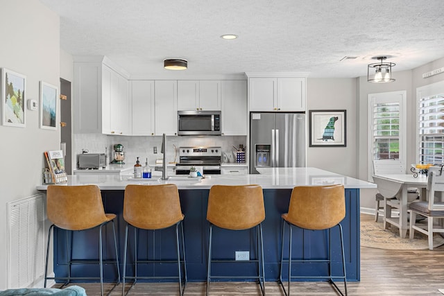 102 Braxton Park Ct, Goodlettsville, TN 37072 - kitchen featuring stainless steel appliances, wood finished floors, light countertops, backsplash, and white cabinetry