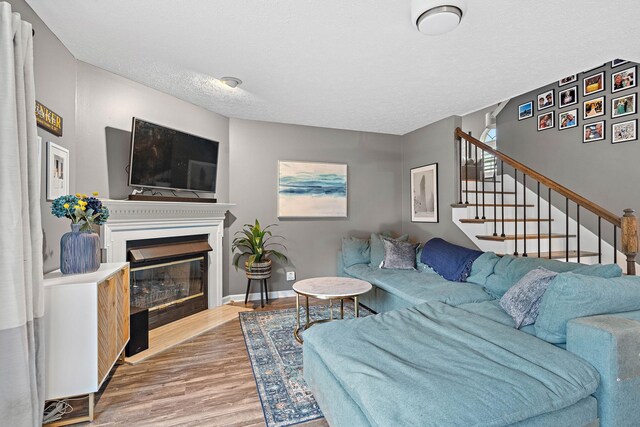 102 Braxton Park Ct, Goodlettsville, TN 37072 - living area with wood finished floors, stairway, a glass covered fireplace, a textured ceiling, and baseboards