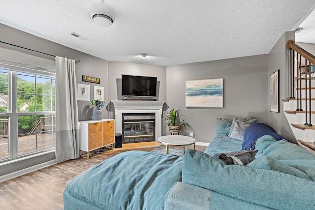 102 Braxton Park Ct, Goodlettsville, TN 37072 - living area featuring stairway, wood finished floors, a textured ceiling, baseboards, and a glass covered fireplace