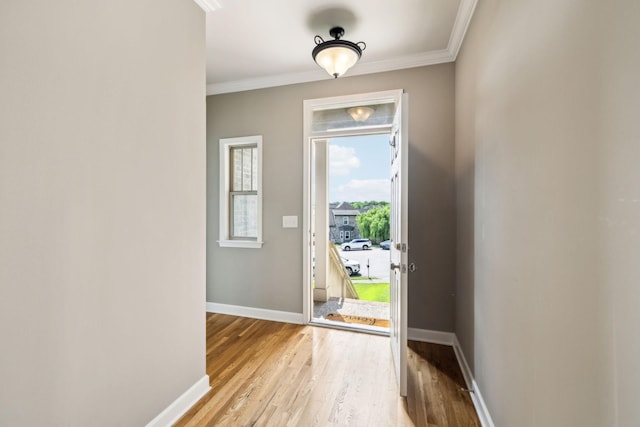 foyer with ornamental molding, light wood-style floors, and baseboards