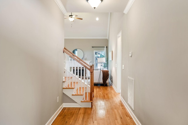corridor with crown molding, stairs, light wood finished floors, and baseboards