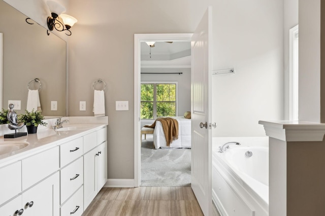 ensuite bathroom with double vanity, a garden tub, and baseboards