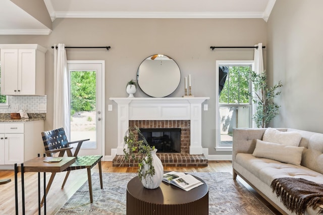 living area with light wood-type flooring, crown molding, a fireplace, and baseboards