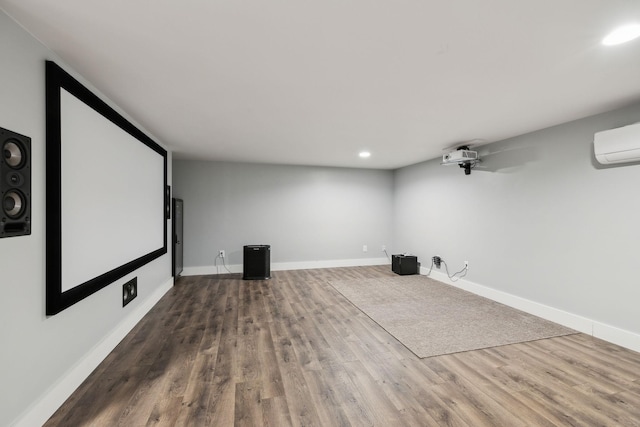 home theater room featuring wood finished floors, recessed lighting, baseboards, and a wall mounted air conditioner