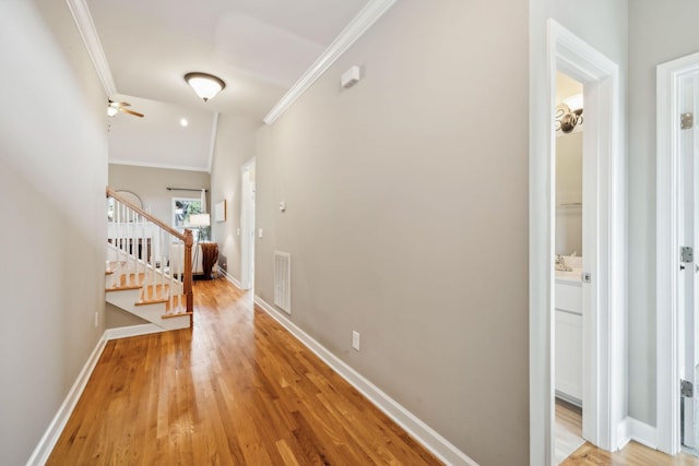 hallway featuring crown molding, stairway, light wood finished floors, and baseboards
