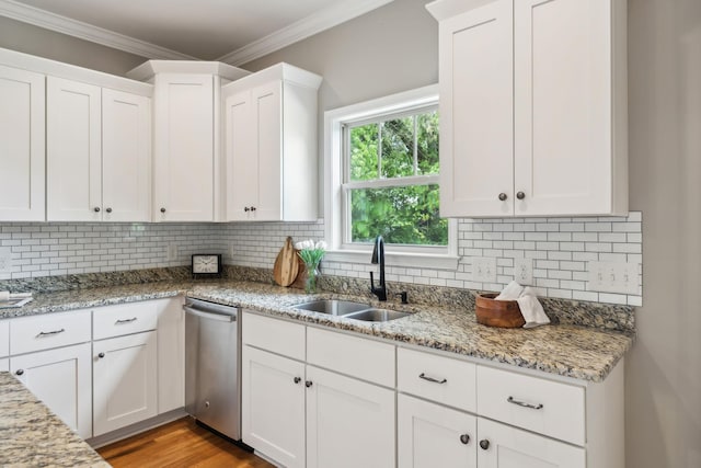 kitchen with a sink, stainless steel dishwasher, white cabinets, crown molding, and backsplash
