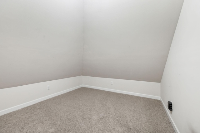 carpeted empty room featuring baseboards and lofted ceiling