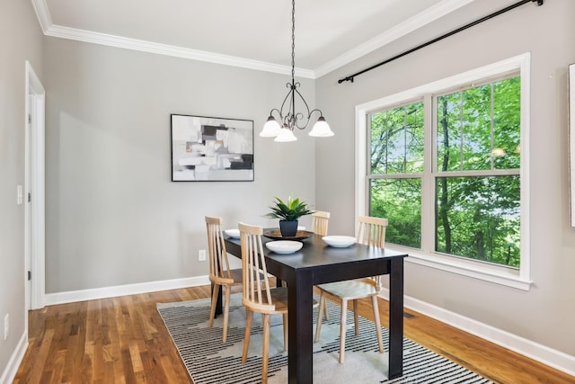 dining space with wood finished floors, a chandelier, crown molding, and baseboards
