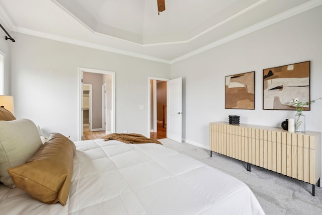 bedroom with crown molding, a tray ceiling, ceiling fan, a spacious closet, and baseboards