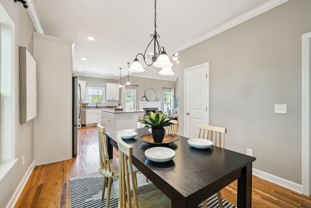 dining room with ornamental molding, a chandelier, light wood finished floors, baseboards, and recessed lighting