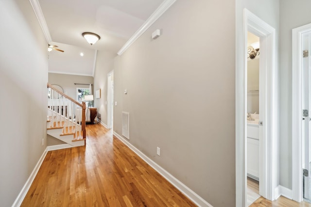 hall with ornamental molding, stairs, light wood finished floors, and baseboards