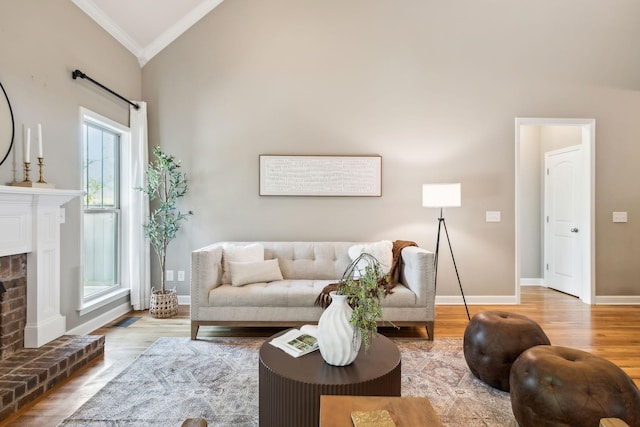 living area featuring ornamental molding, wood finished floors, lofted ceiling, baseboards, and a fireplace