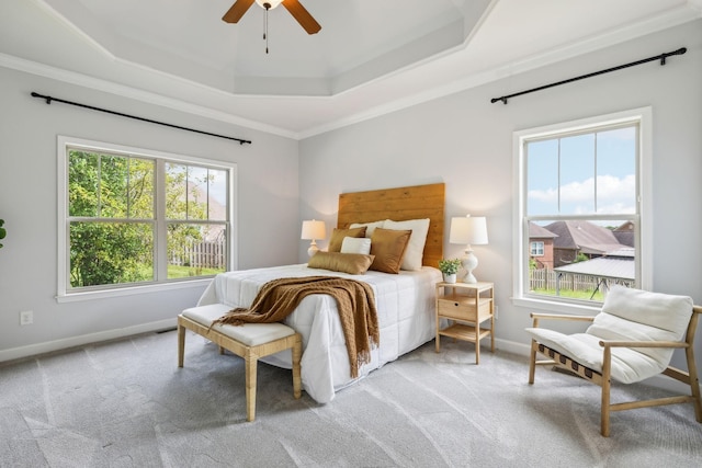 bedroom with a raised ceiling, multiple windows, light colored carpet, and ornamental molding