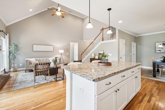 kitchen featuring light wood finished floors, a ceiling fan, white cabinets, a kitchen island, and crown molding