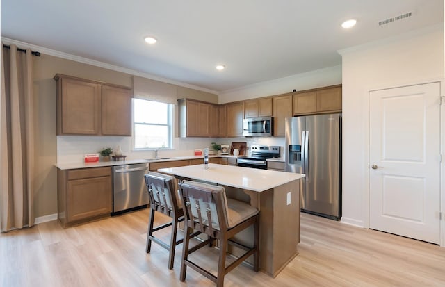3292 Barrel Oak Pass, Columbia, TN 38401 - kitchen featuring appliances with stainless steel finishes, a sink, crown molding, a kitchen bar, and light wood-type flooring