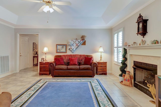 living room with a tray ceiling, baseboards, ceiling fan, light tile patterned flooring, and crown molding