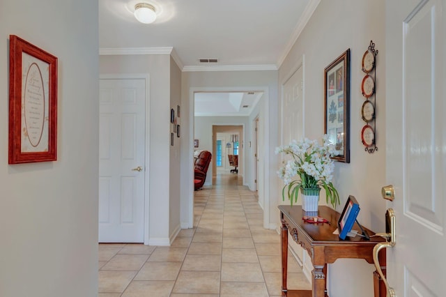 hall with light tile patterned floors, crown molding, and baseboards