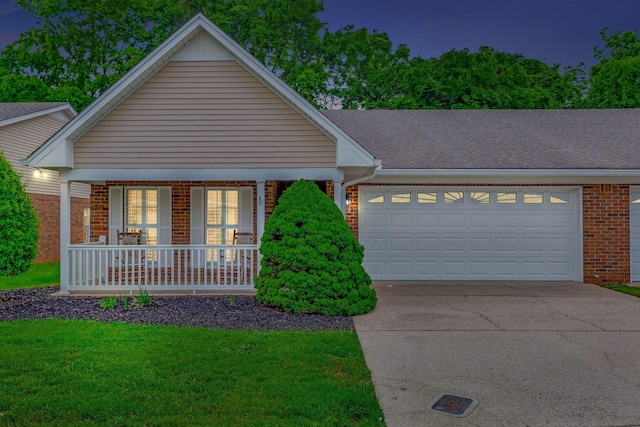 view of front of property with brick siding, covered porch, driveway, a garage, and a front lawn