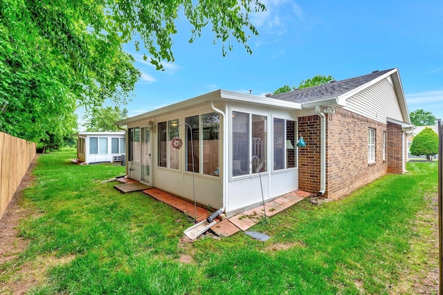 back of property with a sunroom and brick siding