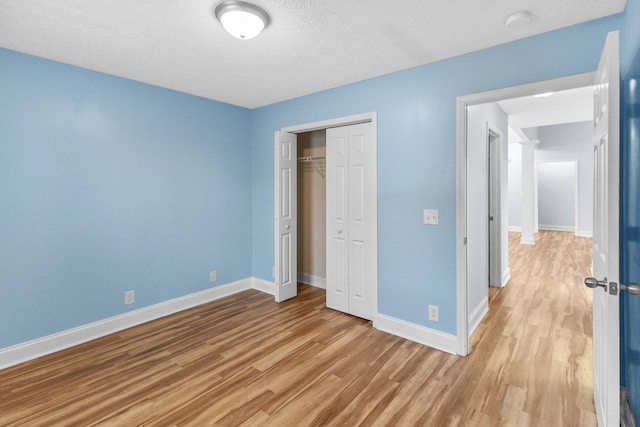 203 Abbigael Dr, Portland, TN 37148 - unfurnished bedroom with light wood finished floors, baseboards, a closet, and a textured ceiling