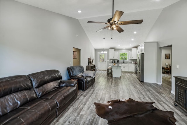 living room featuring high vaulted ceiling, ceiling fan, and light wood-style floors