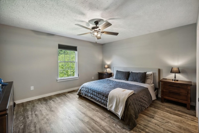 bedroom featuring wood finished floors, baseboards, a textured ceiling, and a ceiling fan