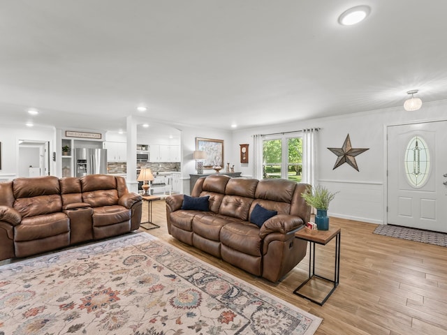 living room featuring light wood-style floors, wainscoting, ornamental molding, and recessed lighting