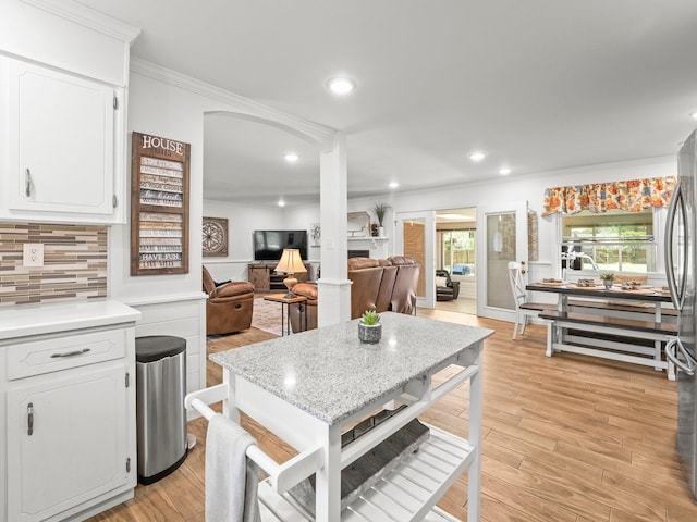 kitchen featuring crown molding, light countertops, decorative backsplash, white cabinets, and light wood finished floors