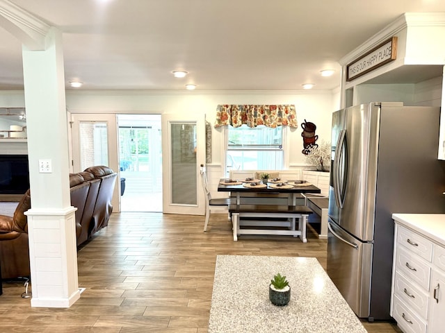 kitchen featuring freestanding refrigerator, crown molding, plenty of natural light, white cabinets, and wood finished floors