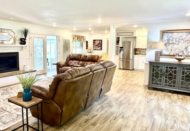 living area featuring crown molding, light wood-style floors, a fireplace, and recessed lighting