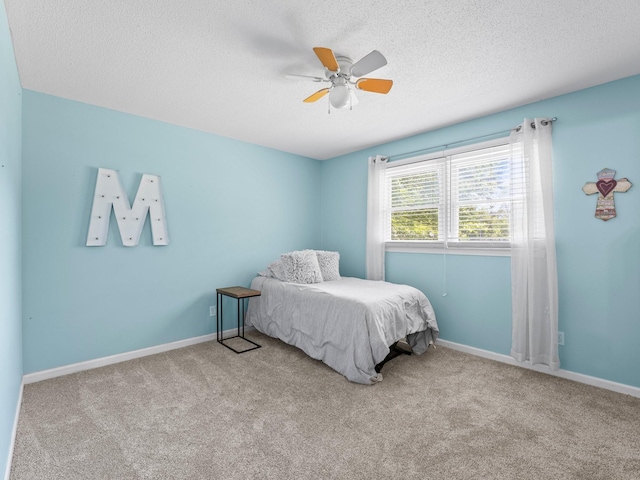carpeted bedroom with a textured ceiling, ceiling fan, and baseboards