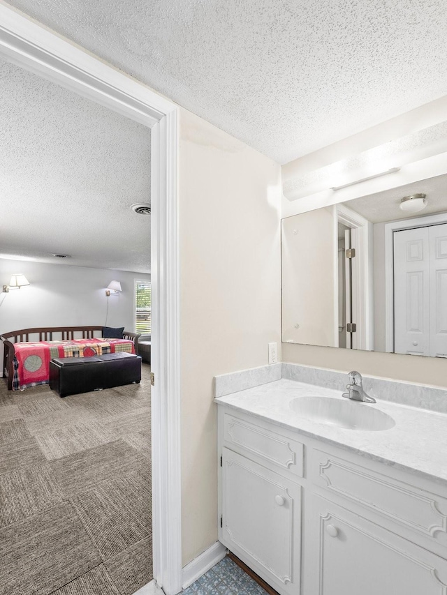 bathroom featuring a textured ceiling, vanity, and ensuite bath