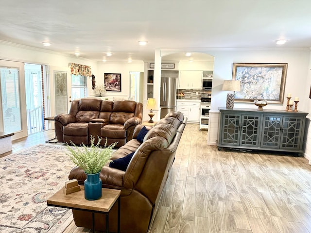 living room featuring light wood-style flooring, crown molding, arched walkways, and recessed lighting